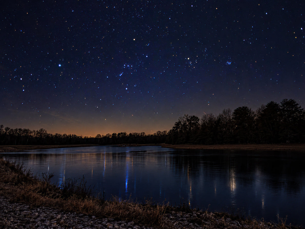 Vue nocturne artistique du lac 16 sous un ciel bleu-violet étoilé au-dessus d’une ligne d’arbres sombre