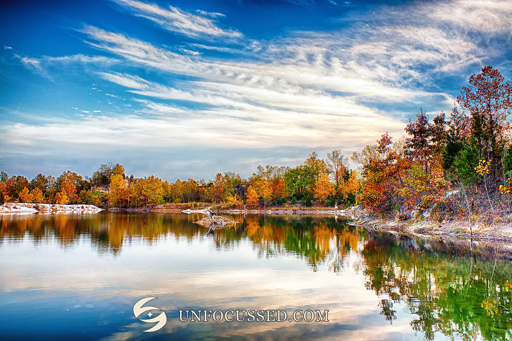 Orange und goldene Bäume neben einem ruhigen See mit zarten weißen Wolken und Spiegelungen in Klondike Park.