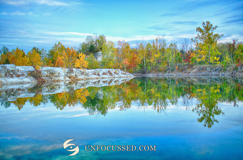 Helles Ufer und gelbgrüne Herbstbäume spiegeln sich im blauen Wasser des Steinbruchsees von Klondike Park.